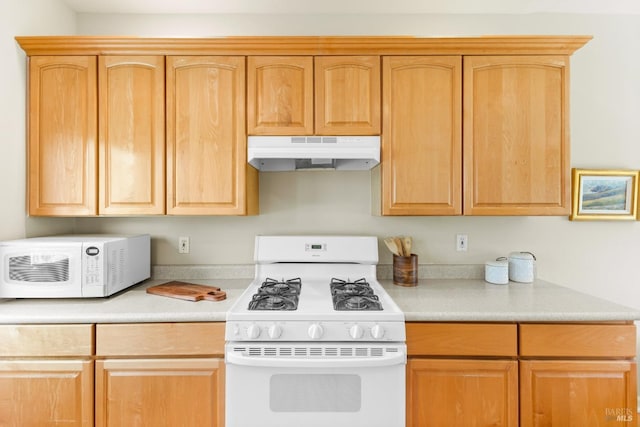 kitchen with light countertops, under cabinet range hood, white appliances, and light brown cabinetry