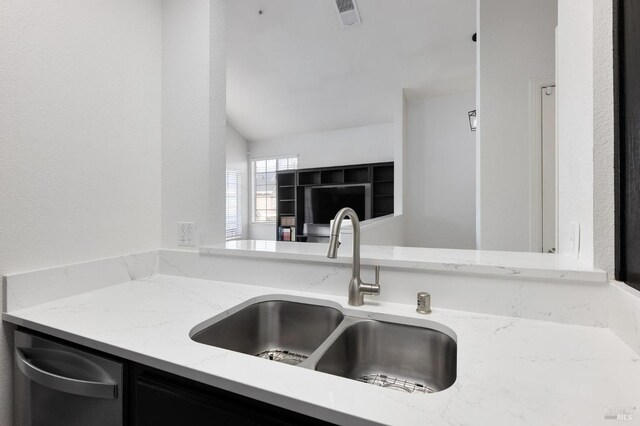 kitchen with stainless steel dishwasher, light stone countertops, a sink, and visible vents