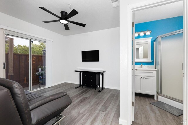 living room featuring baseboards, visible vents, wood finished floors, and a ceiling fan