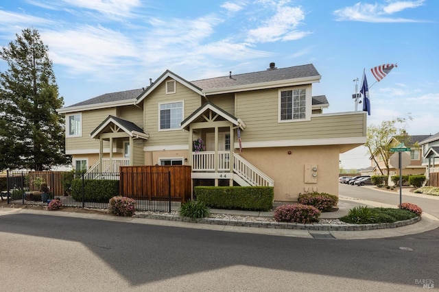 raised ranch featuring stucco siding and a fenced front yard