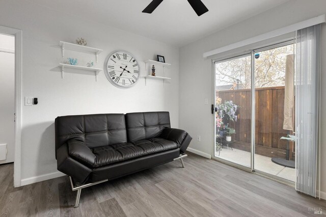 living area with baseboards, wood finished floors, and ceiling fan