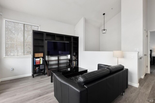 living area featuring vaulted ceiling, wood finished floors, and baseboards
