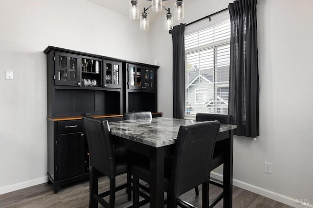 dining room featuring baseboards, wood finished floors, and an inviting chandelier