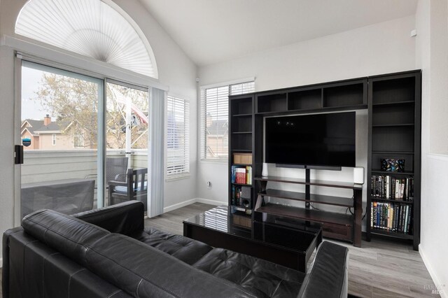 living area featuring baseboards, wood finished floors, and vaulted ceiling