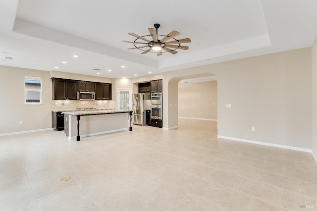 8568 Pinehollow Cir, Discovery Bay, CA 94505 - unfurnished living room featuring a raised ceiling, a ceiling fan, arched walkways, recessed lighting, and baseboards