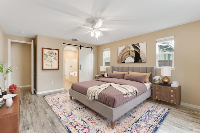 8568 Pinehollow Cir, Discovery Bay, CA 94505 - bedroom featuring a barn door, light wood finished floors, baseboards, ensuite bathroom, and ceiling fan