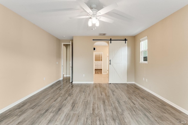 8568 Pinehollow Cir, Discovery Bay, CA 94505 - unfurnished room featuring a barn door, light wood-style flooring, ceiling fan, and baseboards