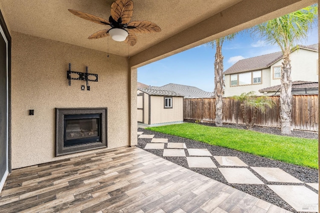 8568 Pinehollow Cir, Discovery Bay, CA 94505 - view of patio featuring a glass covered fireplace, a fenced backyard, ceiling fan, a storage shed, and an outbuilding