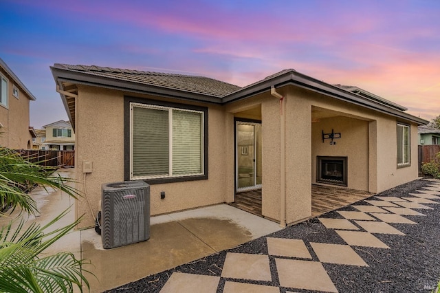 8568 Pinehollow Cir, Discovery Bay, CA 94505 - back of house at dusk with central air condition unit, a patio area, stucco siding, and fence