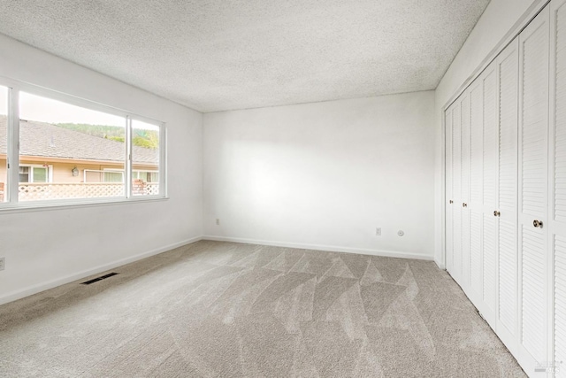 6574 Stone Bridge Rd, Santa Rosa, CA 95409 - unfurnished bedroom with a closet, a textured ceiling, baseboards, light colored carpet, and visible vents