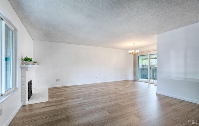6574 Stone Bridge Rd, Santa Rosa, CA 95409 - unfurnished living room with a textured ceiling, a fireplace, an inviting chandelier, and light wood-type flooring