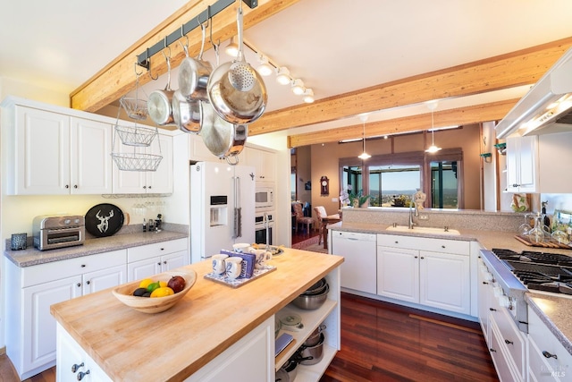 kitchen with a sink, wooden counters, stainless steel appliances, beamed ceiling, and white cabinets
