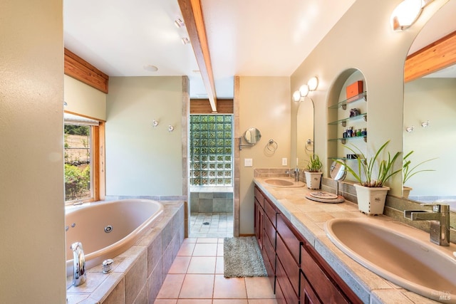 bathroom with a tub with jets, double vanity, tile patterned flooring, and a sink