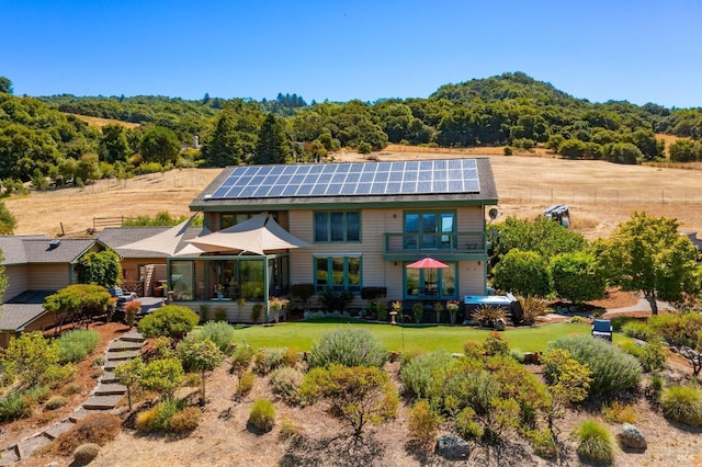 rear view of house featuring solar panels and a yard