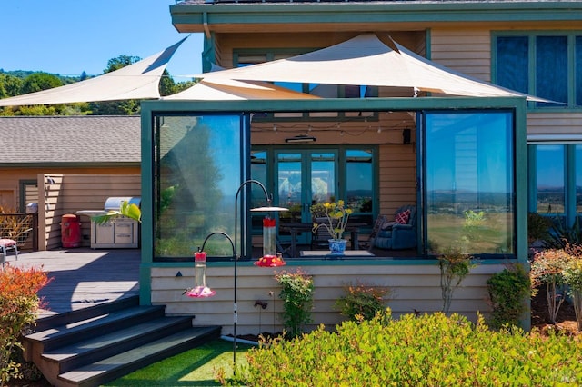 back of property with a sunroom and a deck