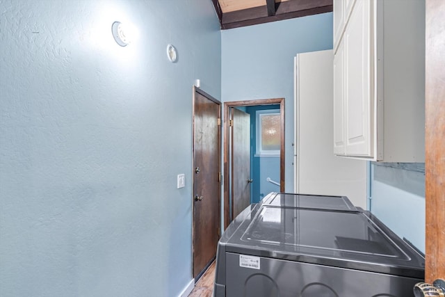 clothes washing area with baseboards, separate washer and dryer, and cabinet space