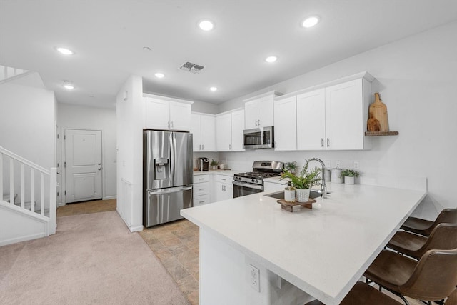 kitchen with a sink, light countertops, a peninsula, stainless steel appliances, and white cabinetry