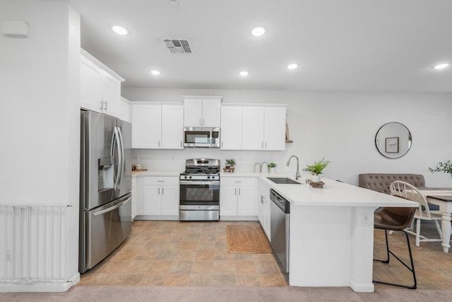 kitchen with visible vents, appliances with stainless steel finishes, a sink, light countertops, and a peninsula