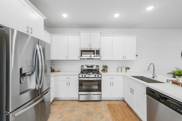kitchen with a sink, light countertops, stainless steel appliances, recessed lighting, and white cabinetry