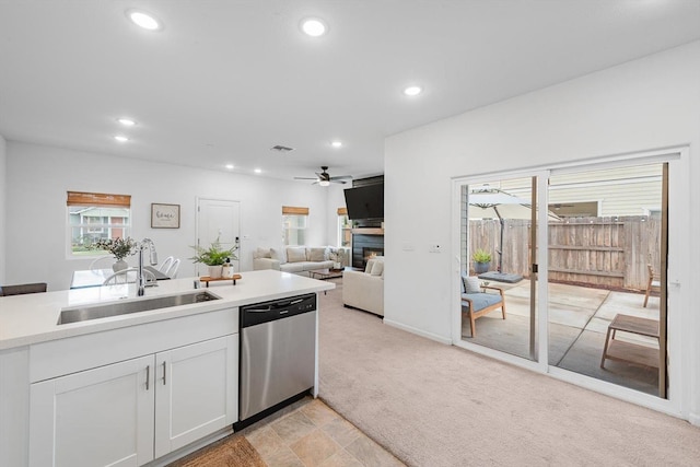 kitchen with stainless steel dishwasher, a ceiling fan, recessed lighting, light colored carpet, and a sink