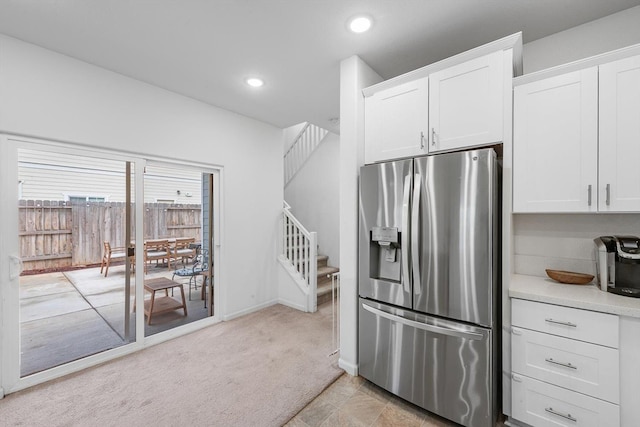 kitchen with white cabinets, stainless steel refrigerator with ice dispenser, light carpet, and light countertops
