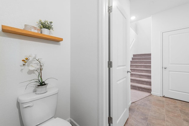 bathroom featuring toilet, baseboards, and stone finish flooring