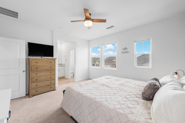 bedroom with visible vents, a ceiling fan, ensuite bathroom, and light colored carpet