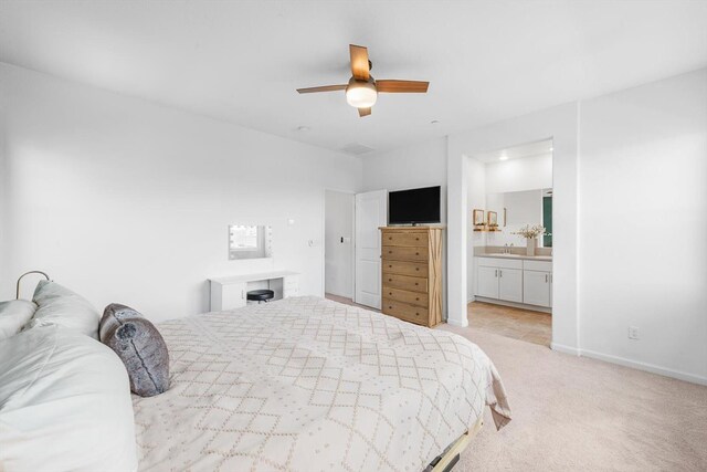 bedroom with light carpet, baseboards, ceiling fan, a sink, and ensuite bath