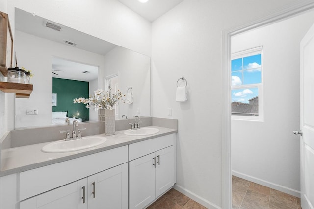 ensuite bathroom with baseboards, visible vents, and a sink