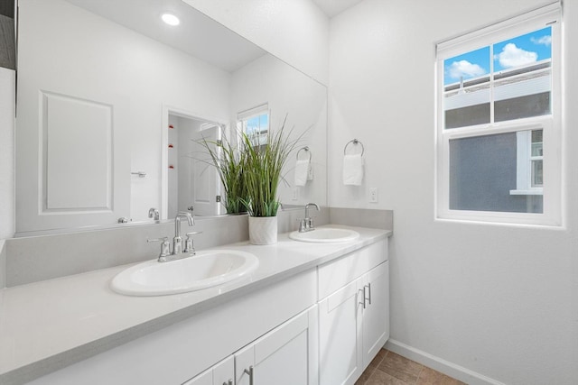 full bath featuring a sink, baseboards, and double vanity