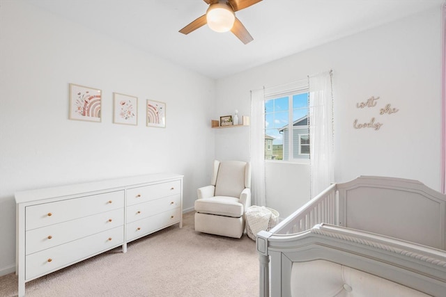 bedroom featuring a ceiling fan, light colored carpet, and a crib
