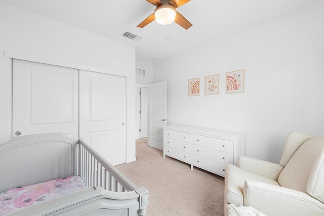bedroom with light colored carpet, a ceiling fan, visible vents, and a closet