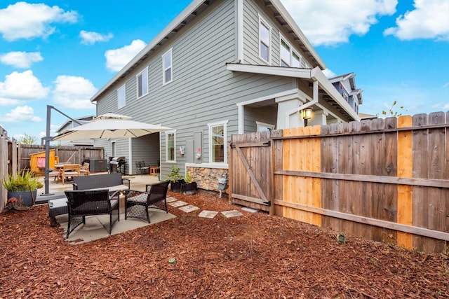 rear view of house featuring a fenced backyard, a gate, and a patio area