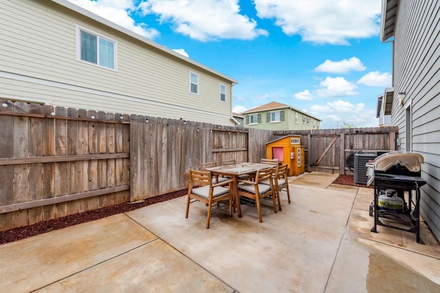 view of patio featuring outdoor dining area, a fenced backyard, central AC, and a gate