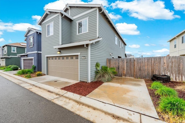 view of front of property with concrete driveway, fence, a residential view, and a garage