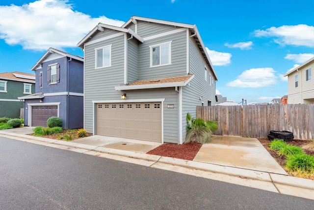 view of front of property featuring concrete driveway, an attached garage, and fence