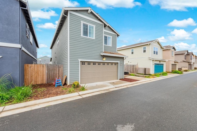 traditional-style house with fence, an attached garage, concrete driveway, and a residential view
