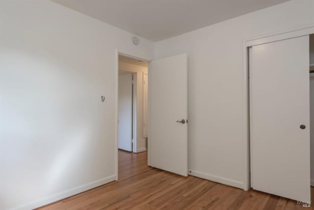 unfurnished bedroom with baseboards, a closet, and light wood finished floors