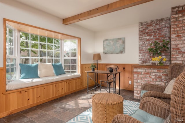 living area with wooden walls, stone finish floor, wainscoting, and beam ceiling