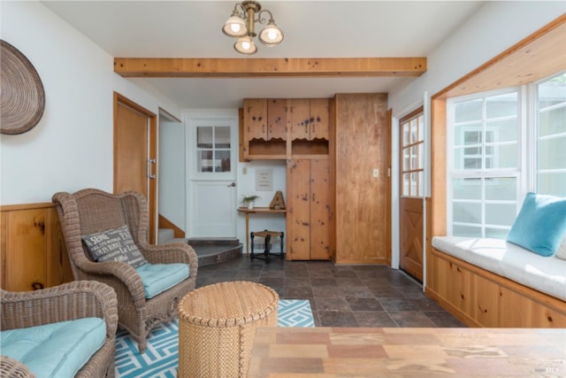 living area featuring stone finish floor and beamed ceiling