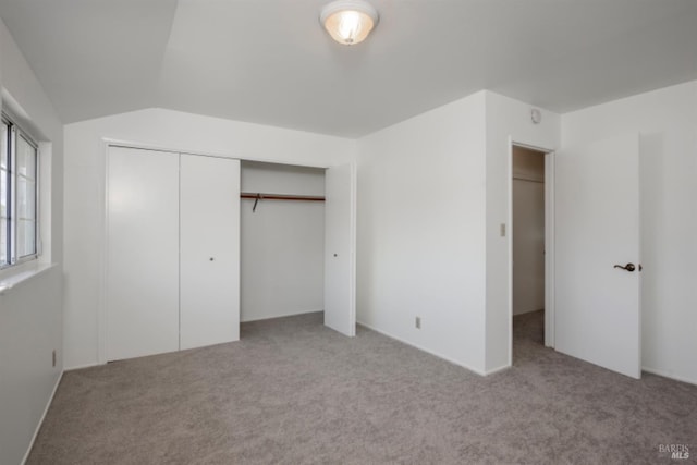 unfurnished bedroom with lofted ceiling, a closet, and carpet floors