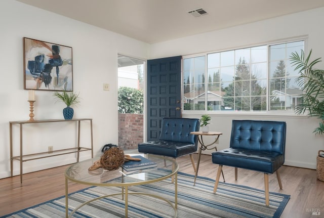 living area with wood finished floors, baseboards, and visible vents