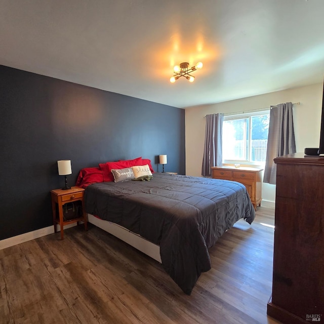 bedroom with baseboards, wood finished floors, and a chandelier