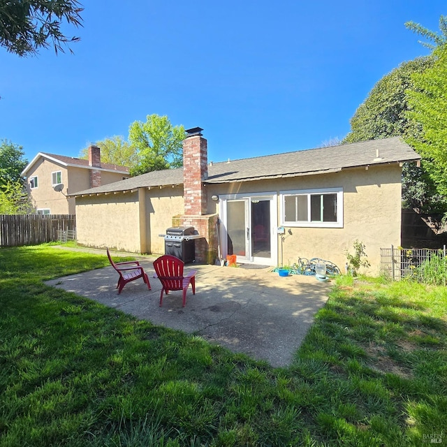 rear view of property with stucco siding, fence, a yard, and a patio area