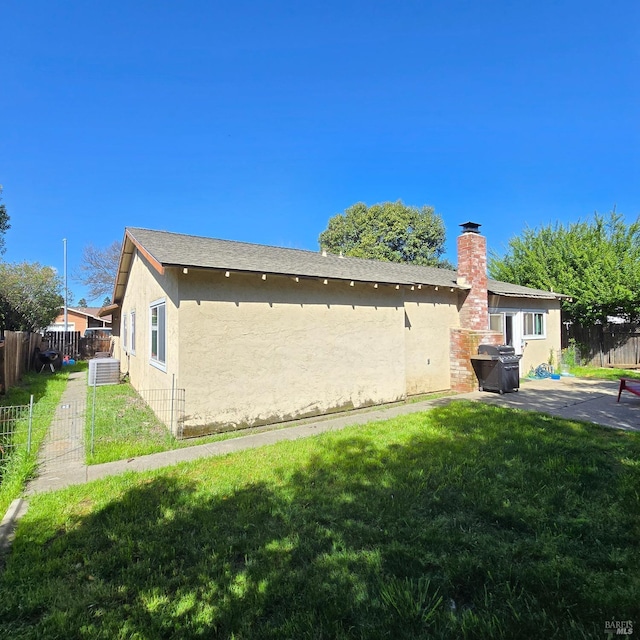 view of home's exterior with stucco siding, fence, a patio, and a yard