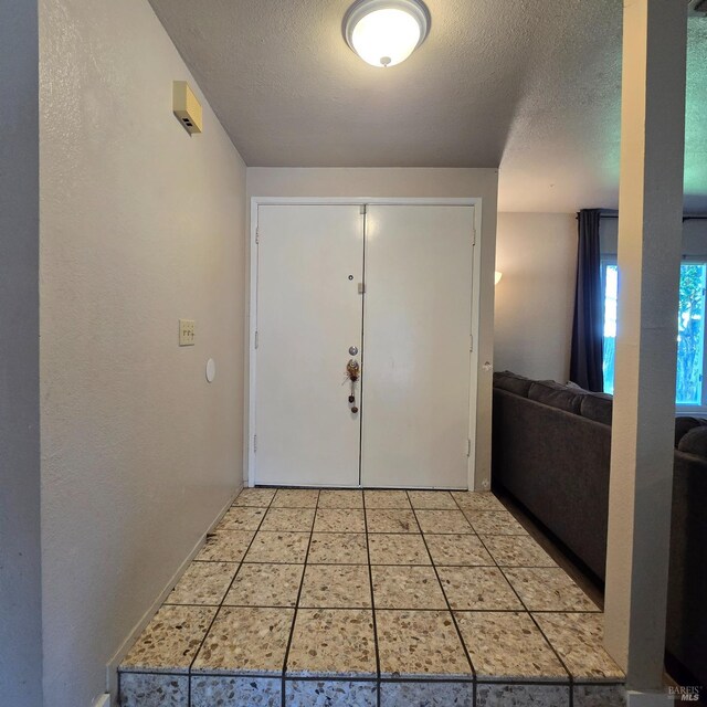 foyer with light tile patterned floors and a textured ceiling
