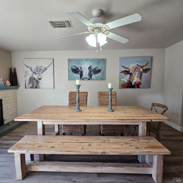 dining room featuring a textured ceiling, visible vents, a ceiling fan, and wood finished floors
