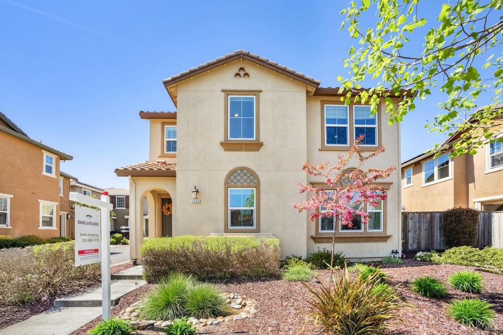 mediterranean / spanish-style house with stucco siding, a tiled roof, and fence