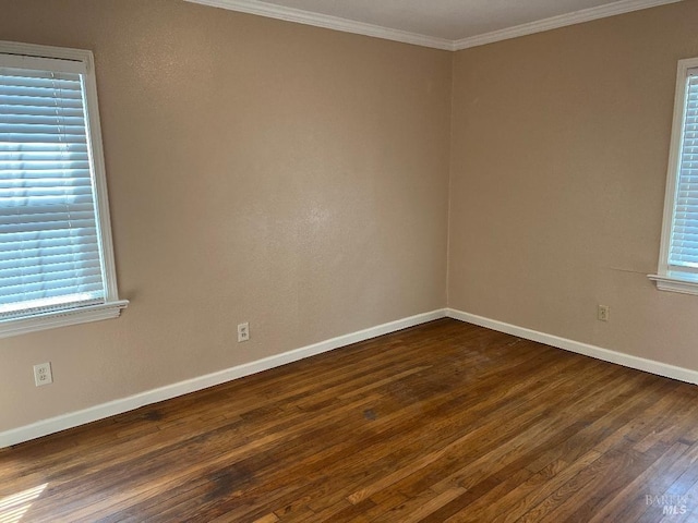 empty room with dark wood-style flooring, ornamental molding, and baseboards