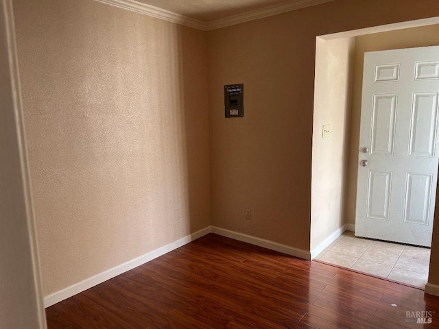unfurnished room with baseboards, light wood-type flooring, and ornamental molding